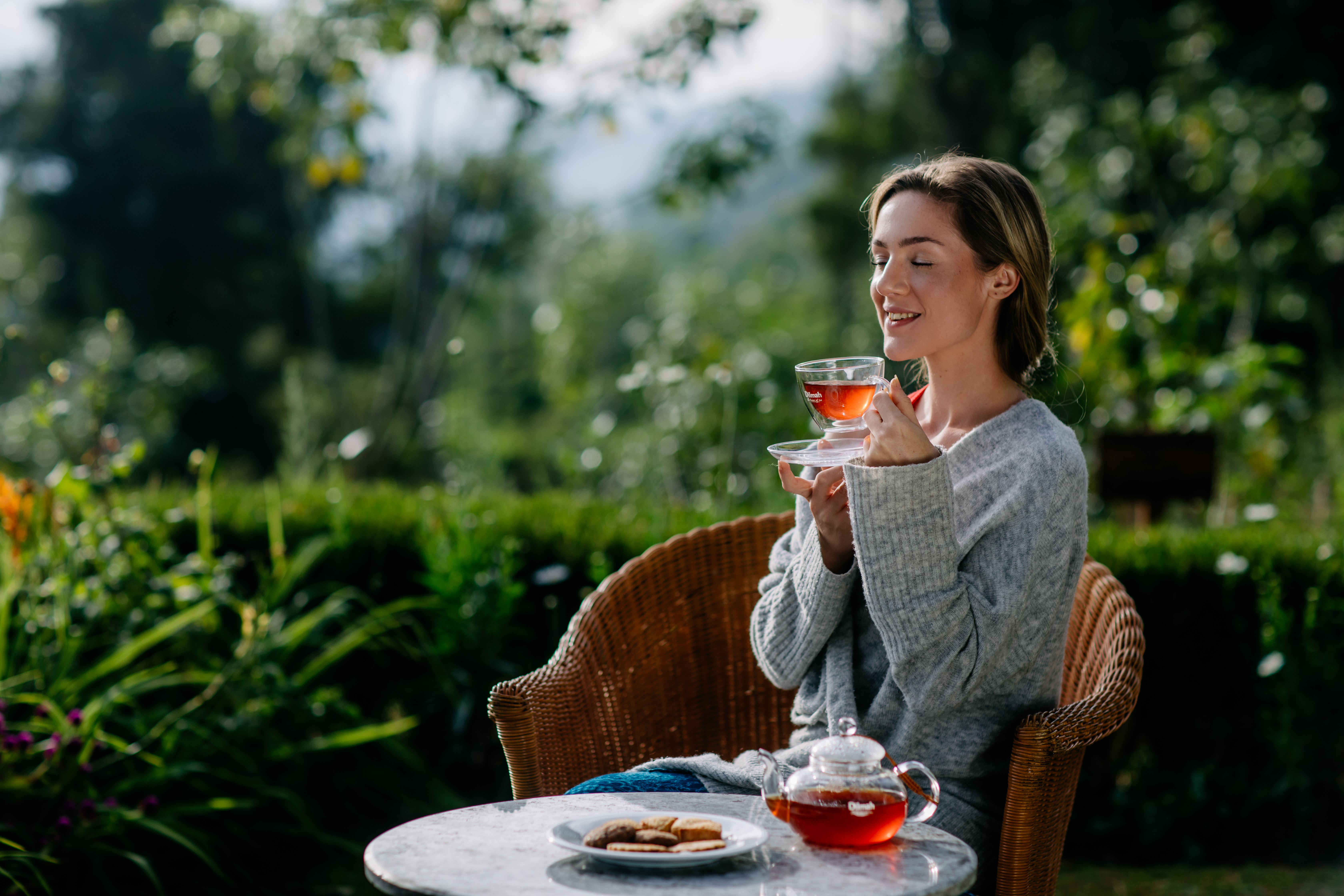 Kobieta rozkoszująca się cejlońską herbatą Dilmah Ceylon Tea na tarasie przed domem.