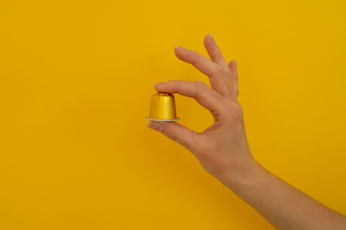 Niewielka, ale pełna doskonałej kawy złota kapsułka Saquella Gran Cru Espresso Ricco trzymana w dłoni. 