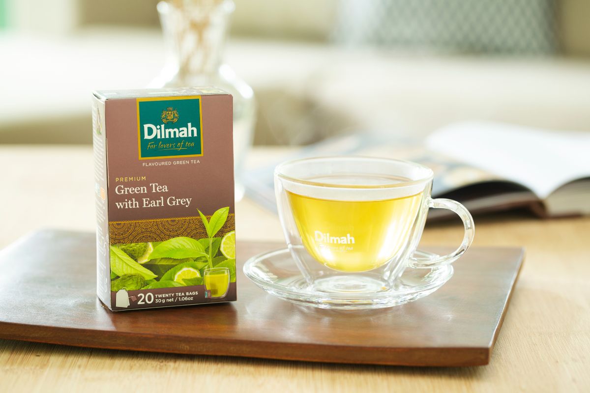 Herbata zielona Earl Grey w przezroczystej filiżance. Obok opakowanie Dilmah Green Tea with Earl Grey.