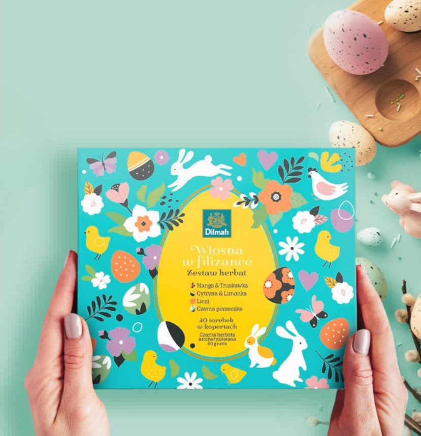 Kobieta podarowuje zestaw herbat na święta Dilmah Easter Gift Pack„Wiosna w filiżance”. W tle wielkanocne dekoracje.